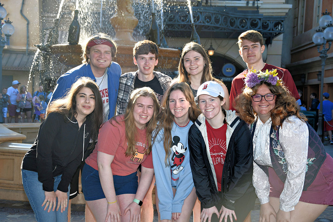 A group of 9 college students smiling in front of a fountain at Disney World